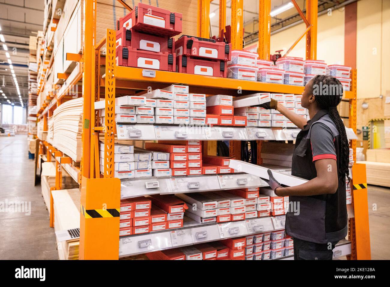 Saleswoman arranging merchandise in rack at hardware store Stock Photo