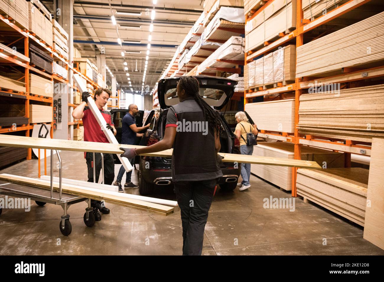 Sales staff helping customers loading planks at hardware store Stock Photo