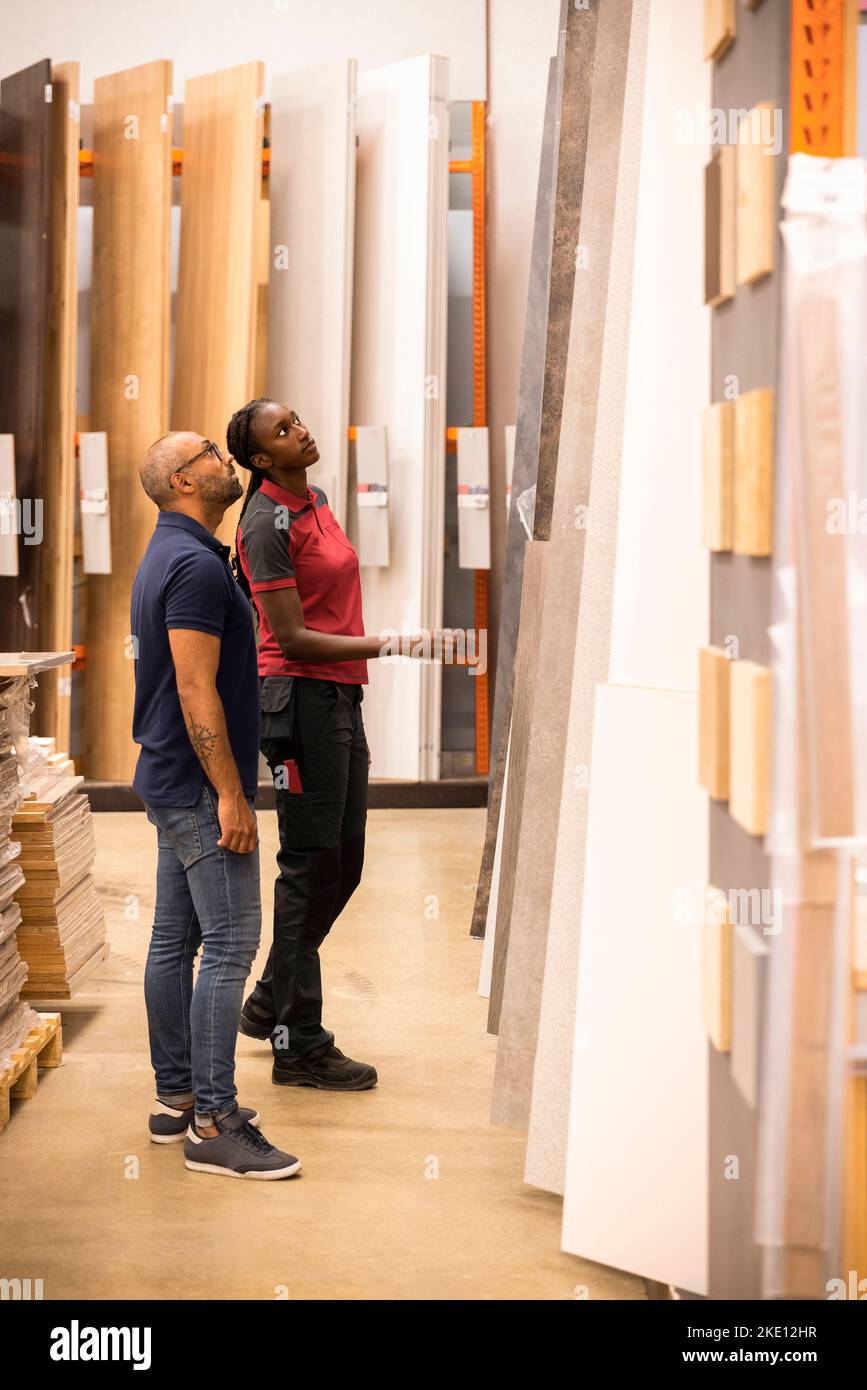 Customer and sales staff looking up while selecting laminated boards at