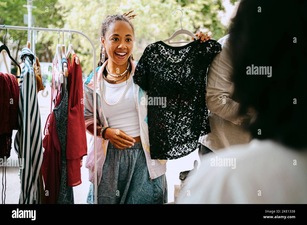 Excited female customer holding dress while talking to merchant at flea market Stock Photo