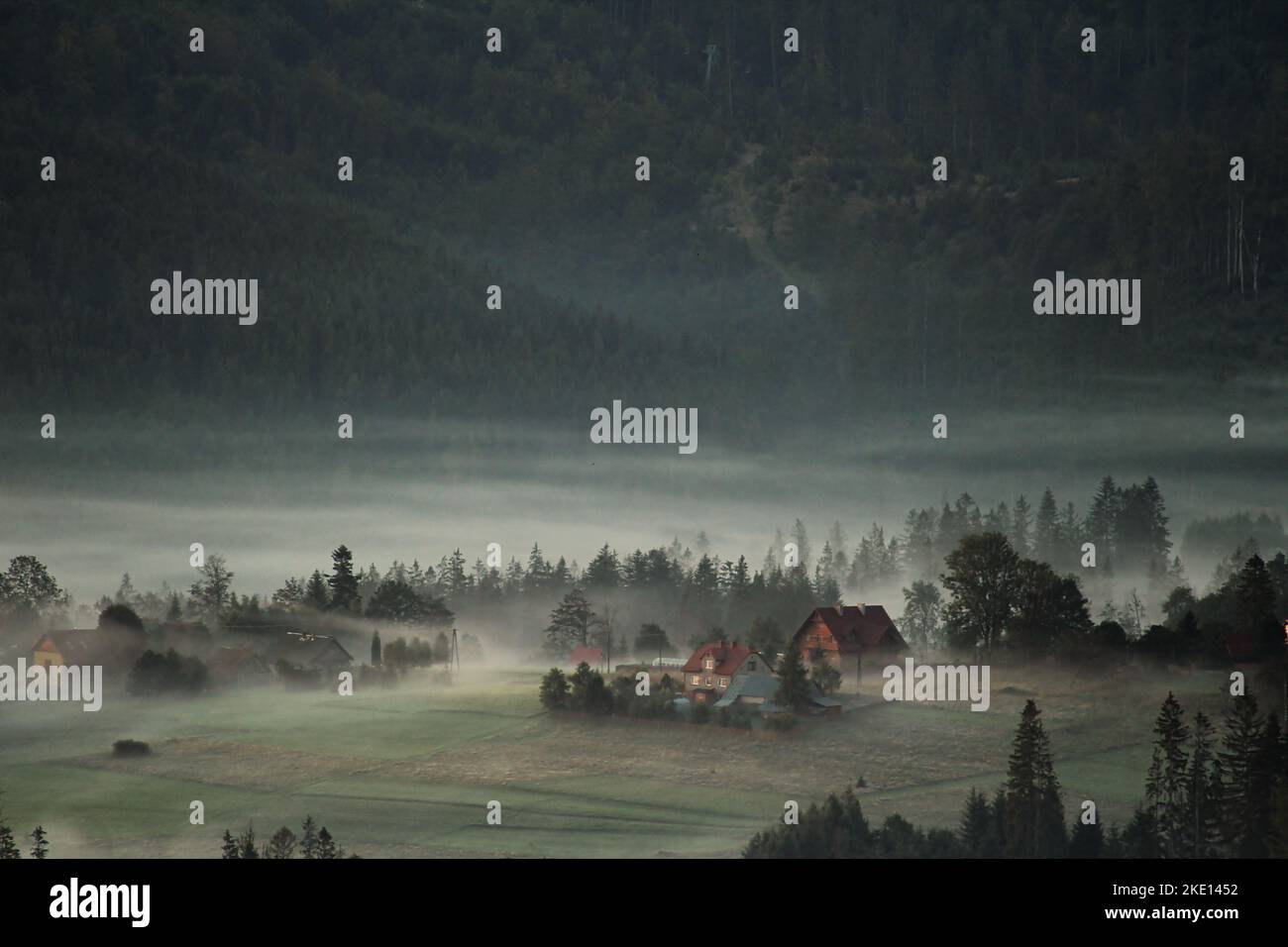 A beautiful view of a valley with trees and house covered in fog Stock ...