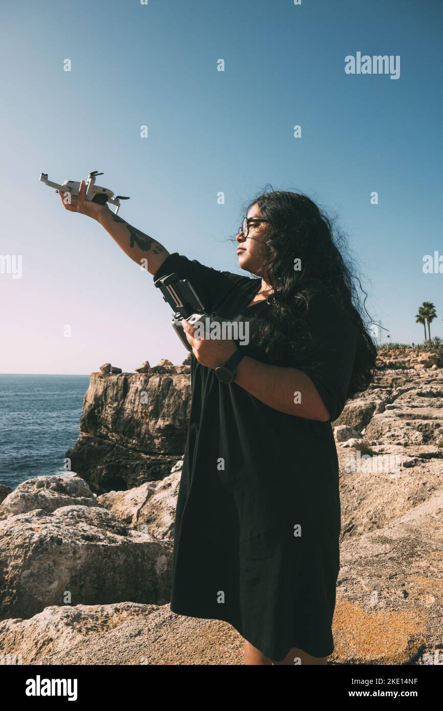 woman with drone, looking to the side black dress and remote control Stock Photo