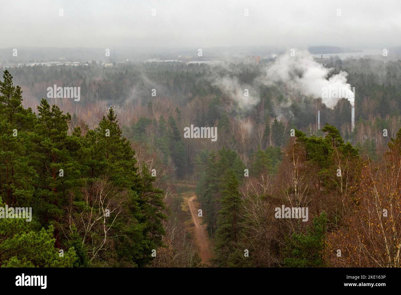 Forest mountain trail, industrial pipes with smoke. Foggy morning. Stock Photo