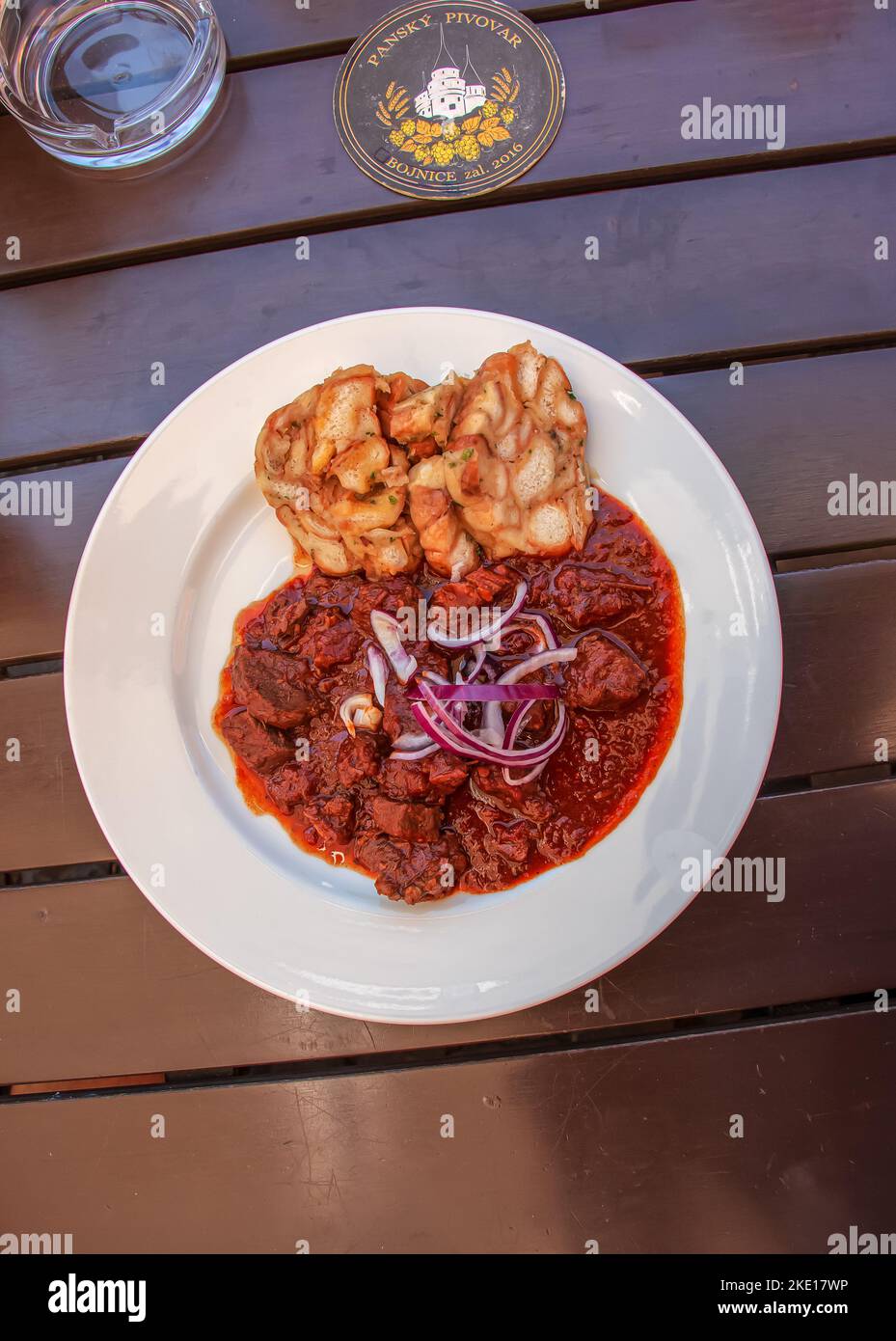 Bojnice, Slovakia - 06.11.2022: Beef goulash with czech dumplings on a white plate on a wooden table in a bar. Stock Photo