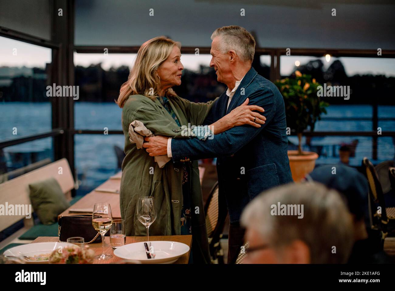 Smiling senior couple greeting each other in restaurant Stock Photo