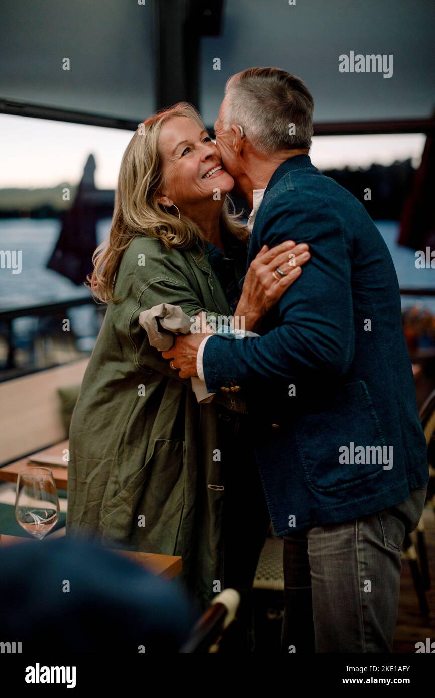 Smiling senior blond woman embracing man in restaurant Stock Photo