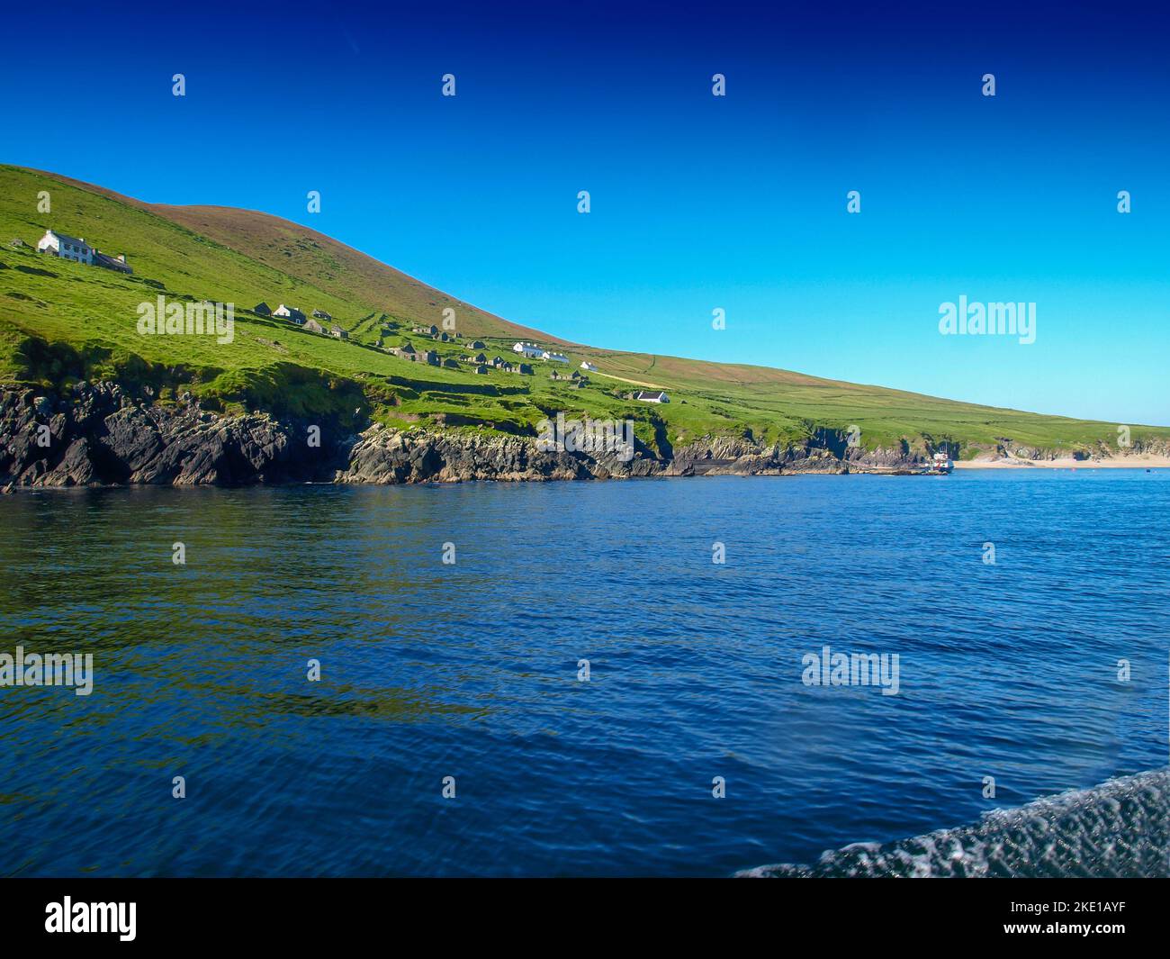 Abandoned settlement on Blasket island, view from a fishing boat near the Slea Head on the Dingle Peninsula in Ireland with a clear deep blue sky Stock Photo