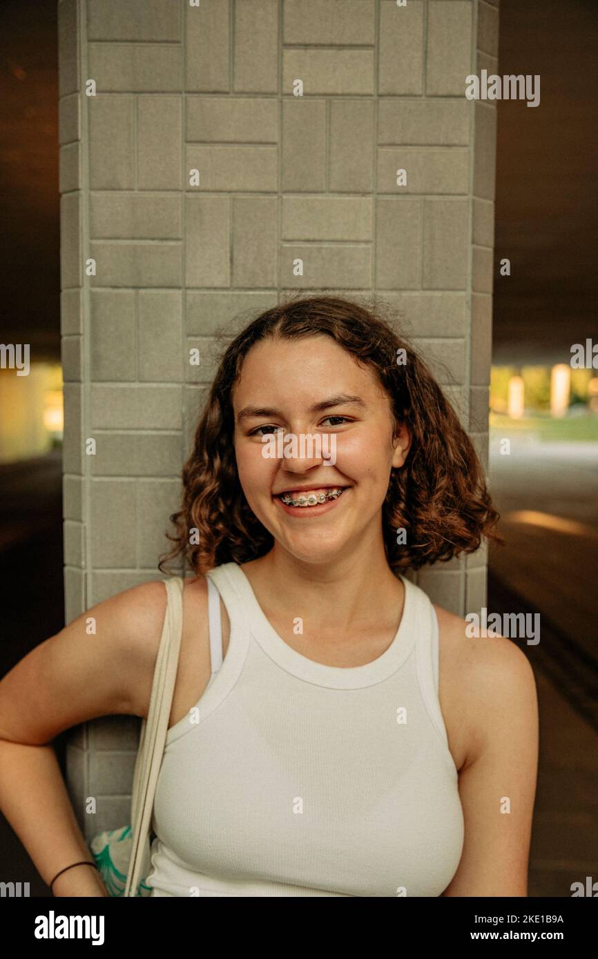 Portrait of happy teenage girl with medium-length hair against column Stock Photo