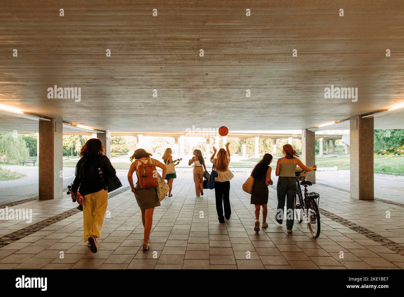 Rear view of teenage girls walking together under bridge Stock Photo