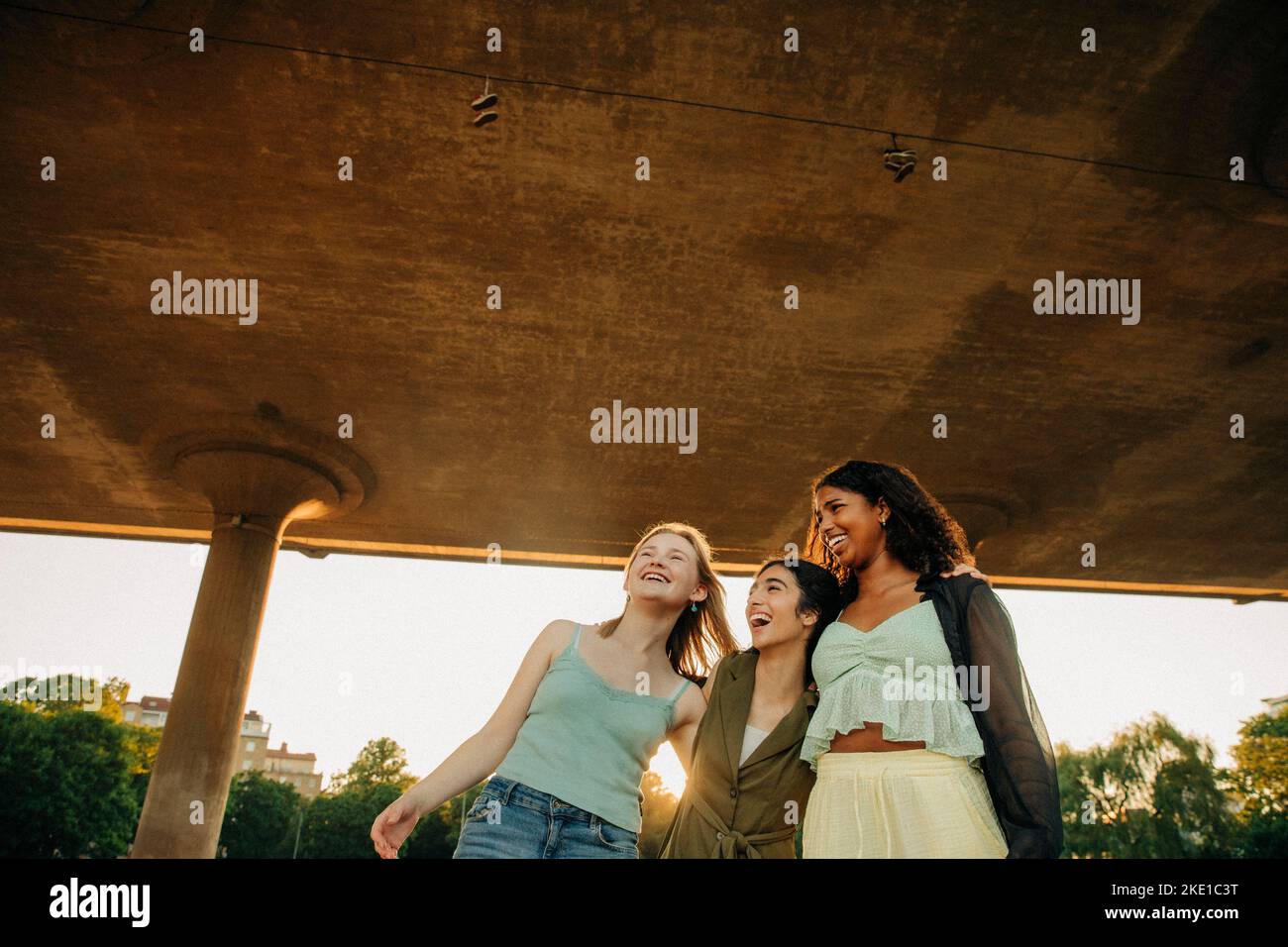 Cheerful teenage female friends enjoying under bridge Stock Photo