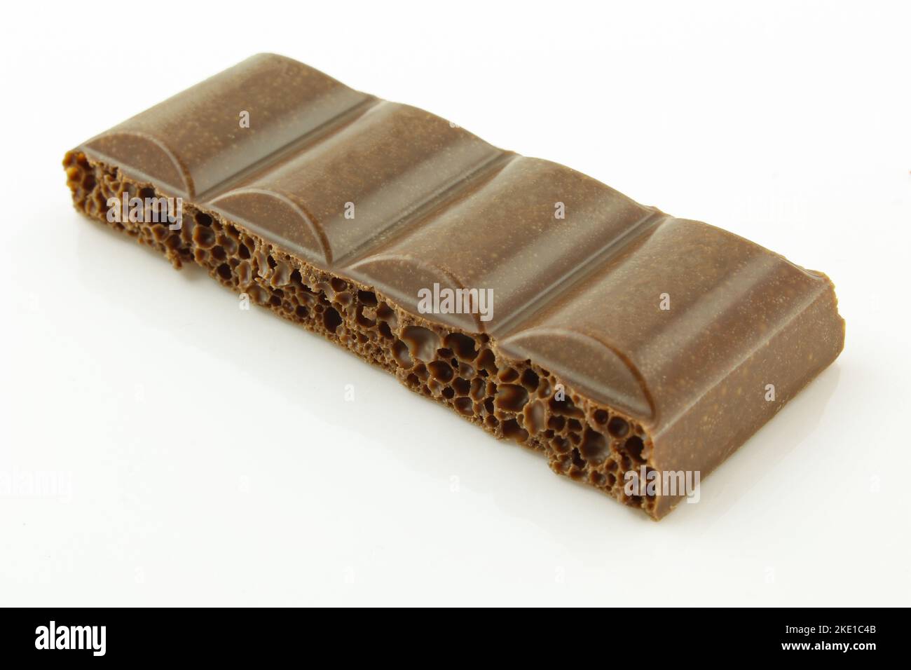 Piece of bubbly milk chocolate isolated on white background Stock Photo