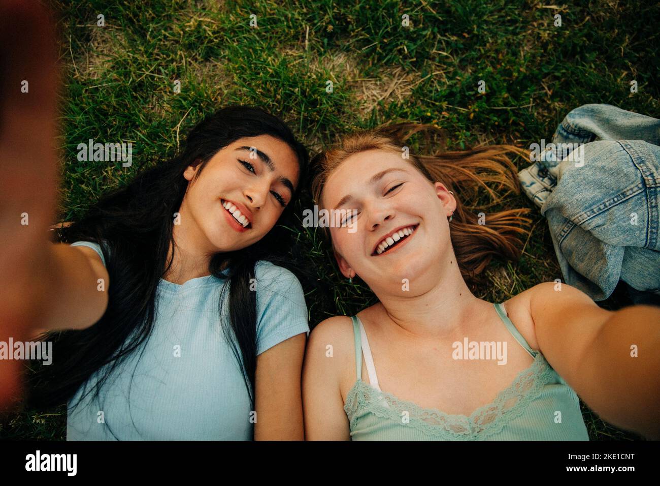 Portrait of happy teenage girls lying on grass at park Stock Photo