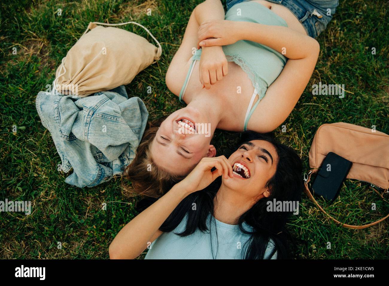 Cheerful teenage girls lying together at park Stock Photo