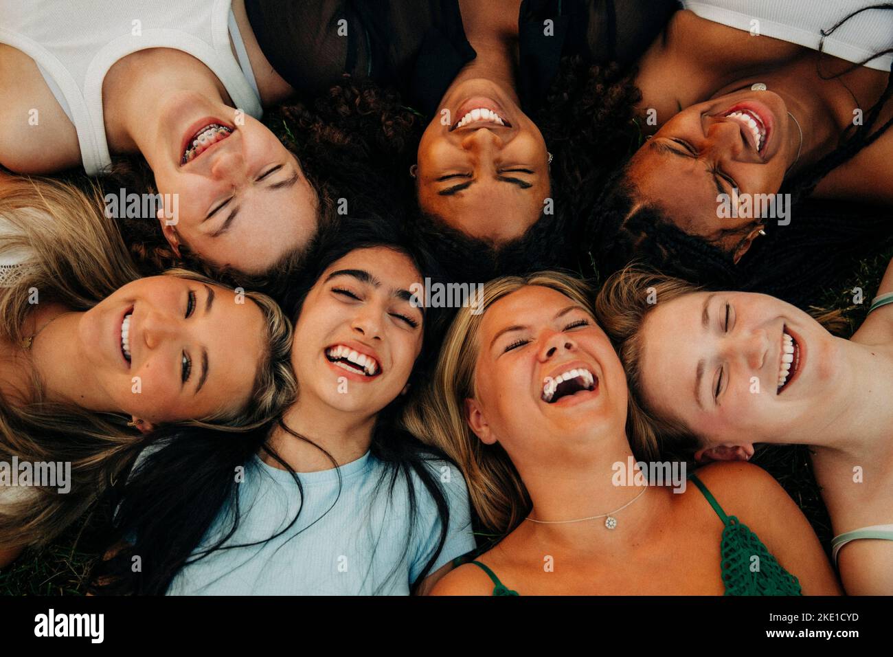 Multiracial cheerful female friends lying while enjoying at park Stock Photo