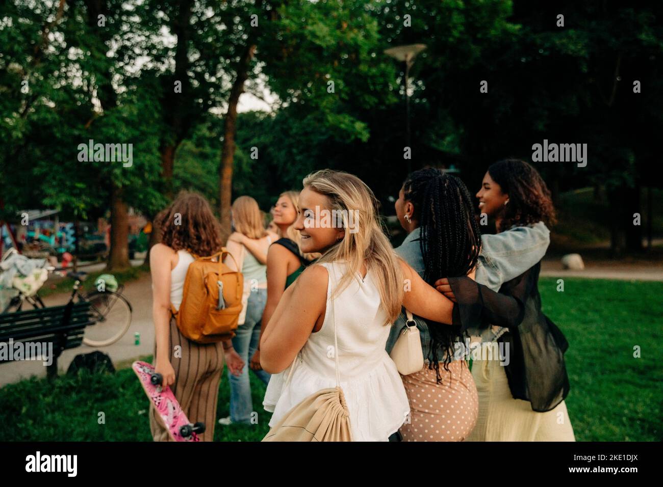 Smiling blond teenage girl walking with female friends at park Stock Photo