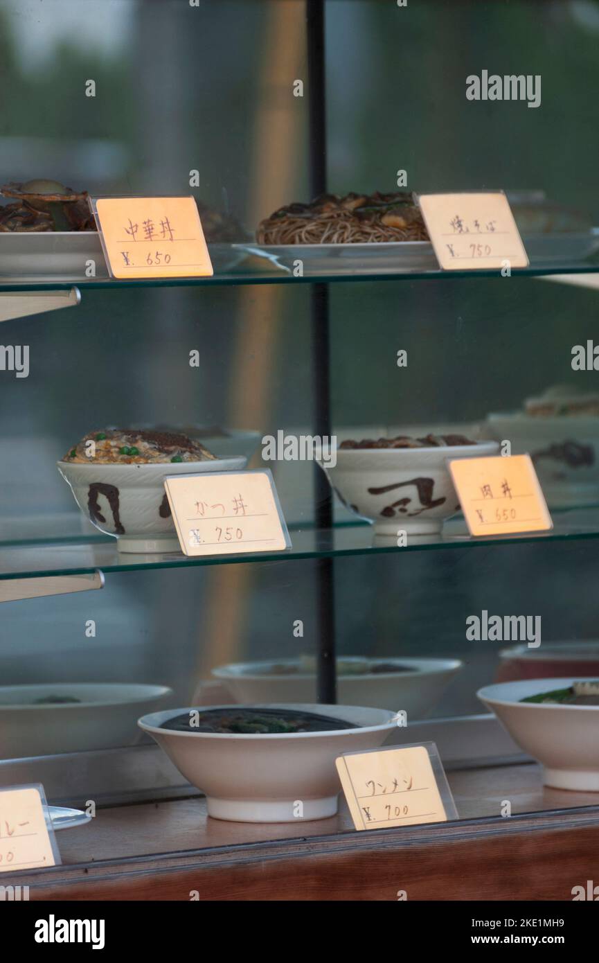 Bowls of rather faded wax food displays mark a restaurant window in