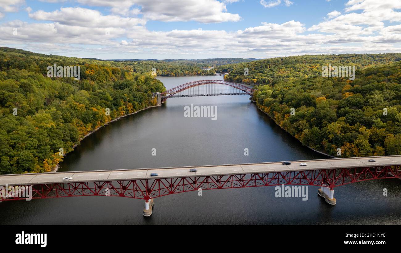 A drone shot of Taconic State Parkway over the New Croton Reservoir between greenery landscapes and AMVETS Memorial in the background with cloudy sky Stock Photo