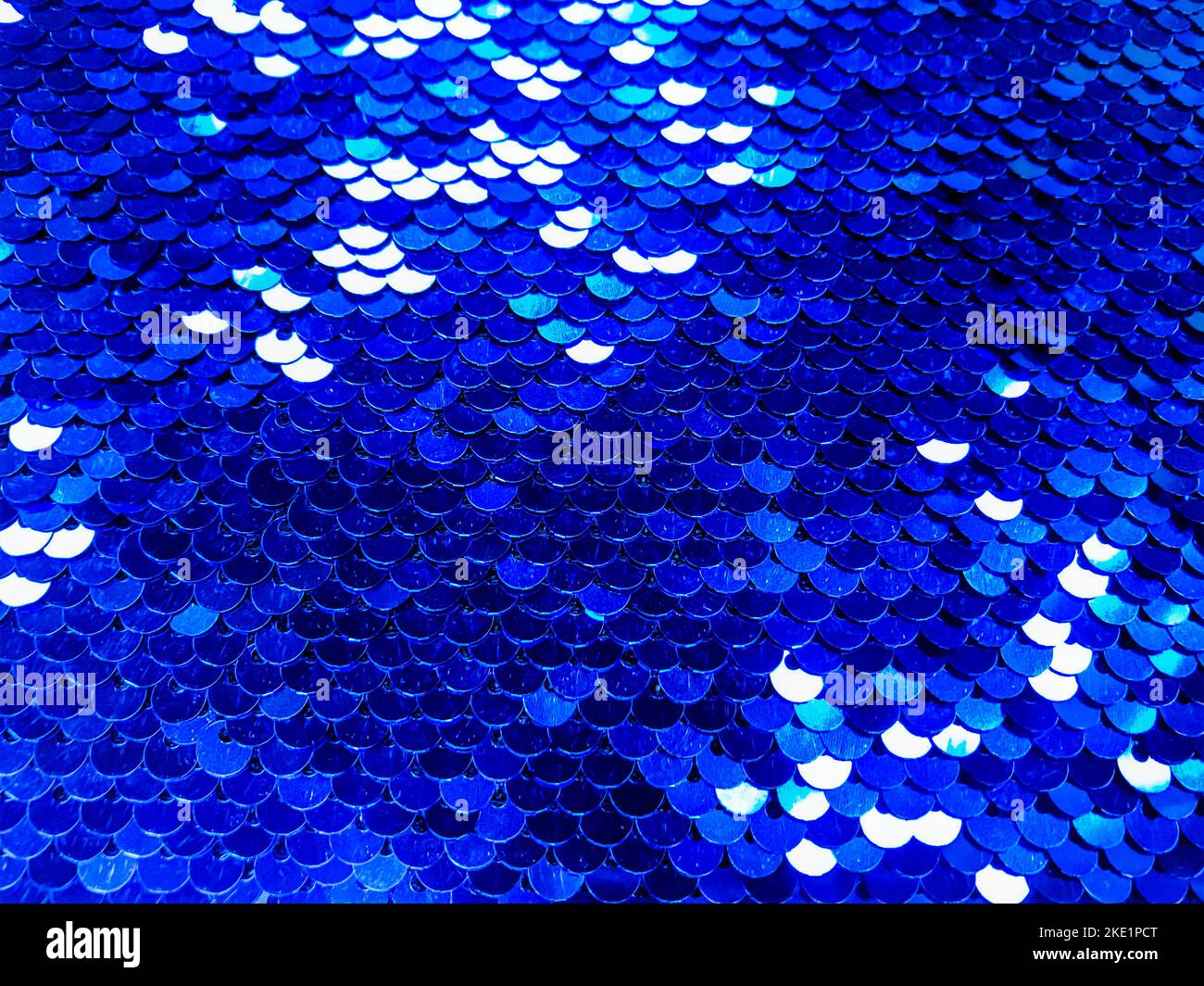 Lots of colorful sequins in blue colors sewn on fabric as scales. Beautiful shiny texture background Stock Photo