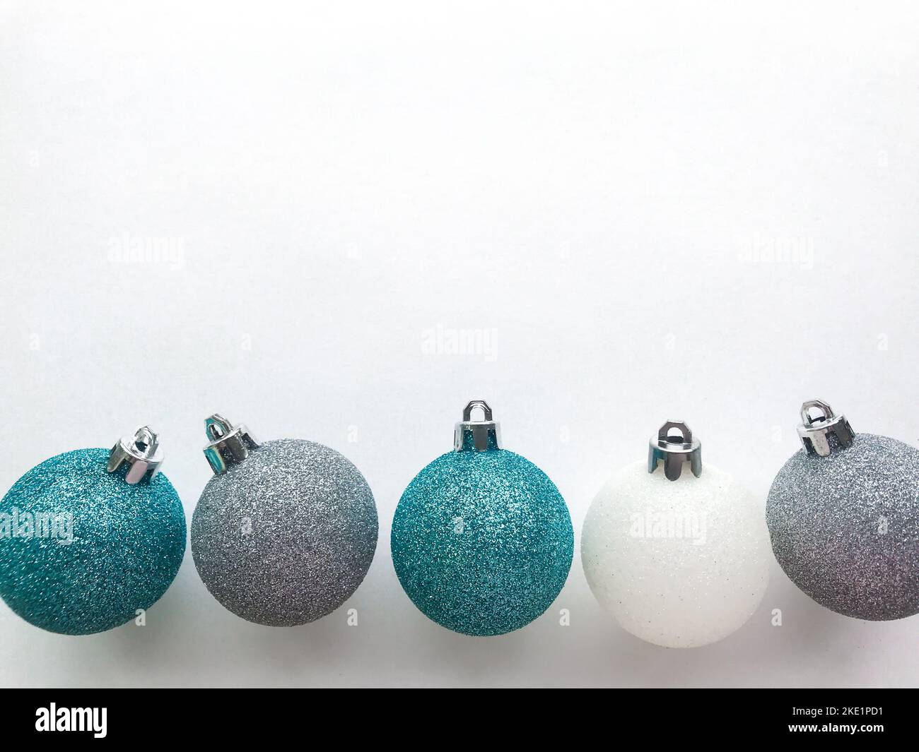 Shiny Christmas balls of blue turquoise, white, silver color, lie in a row on a white background with space for text. The concept of Christmas and New Stock Photo