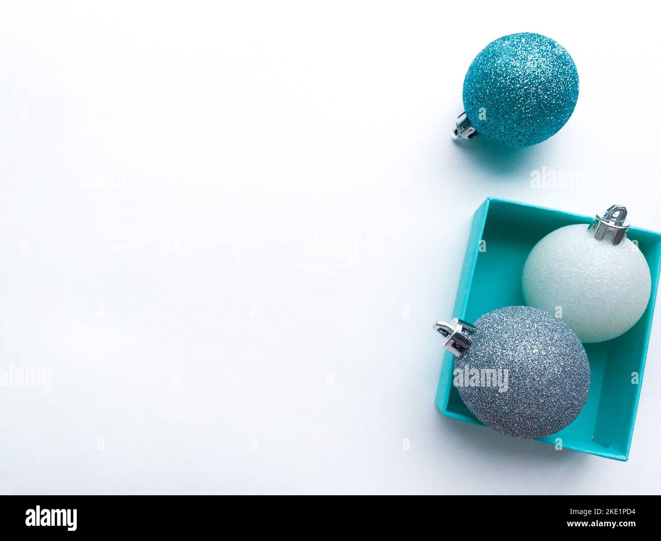 Turquoise jewel boxes inside of which is a shiny Christmas balls white, blue and silver color on the right. White background. Copy space. Stock Photo