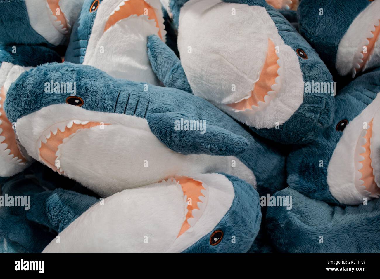 A lot of plush toys in the form of blue and gray sharks with open jaws with teeth piled in a heap. Stock Photo