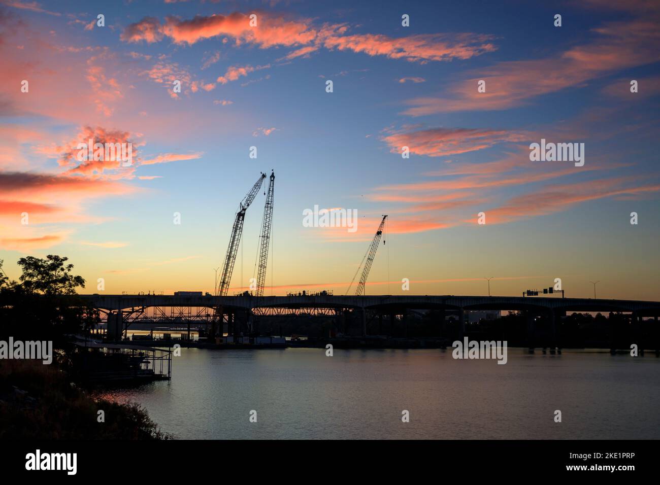 Silhouette of construction cranes working on the Arkansas River Bridge, Interstate 30, in downtown Little Rock, at sunrise. Stock Photo