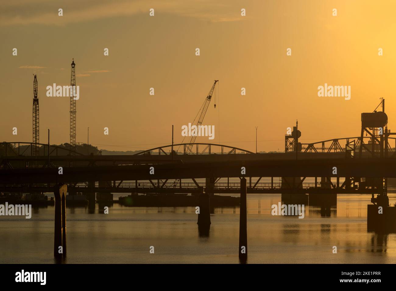 Silhouette of construction cranes working on the Arkansas River Bridge, Interstate 30, in downtown Little Rock, at sunrise. Stock Photo