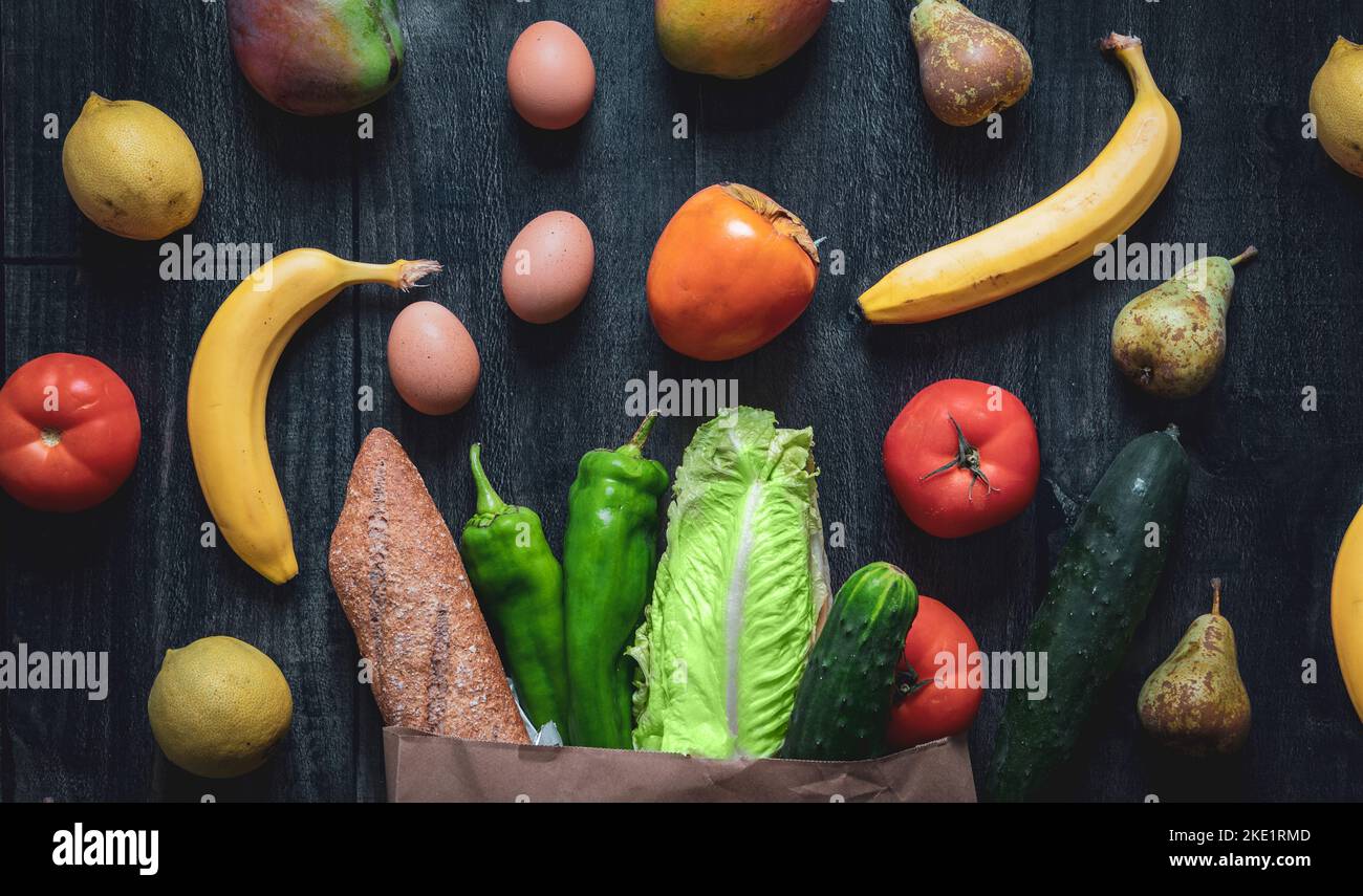 Closeup of a shopping bag full of vegetables, fruits, eggs and bread on a wooden background. Background for greengrocers and supermarkets. Home delive Stock Photo