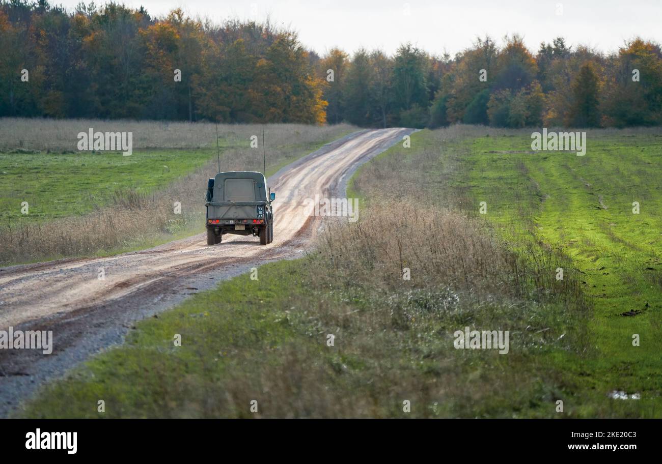 British army Land Rover Defender Wolf 4x4 medium utility vehicle driving along a mud track, military exercise Wilts UK Stock Photo