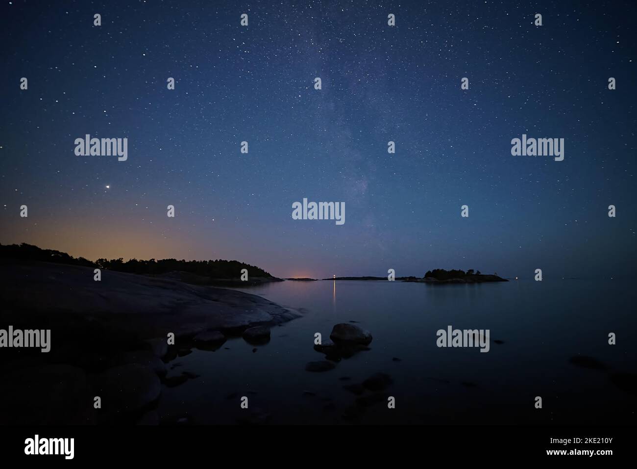 A lake reflecting the starry sky with trees and a night sky in the ...