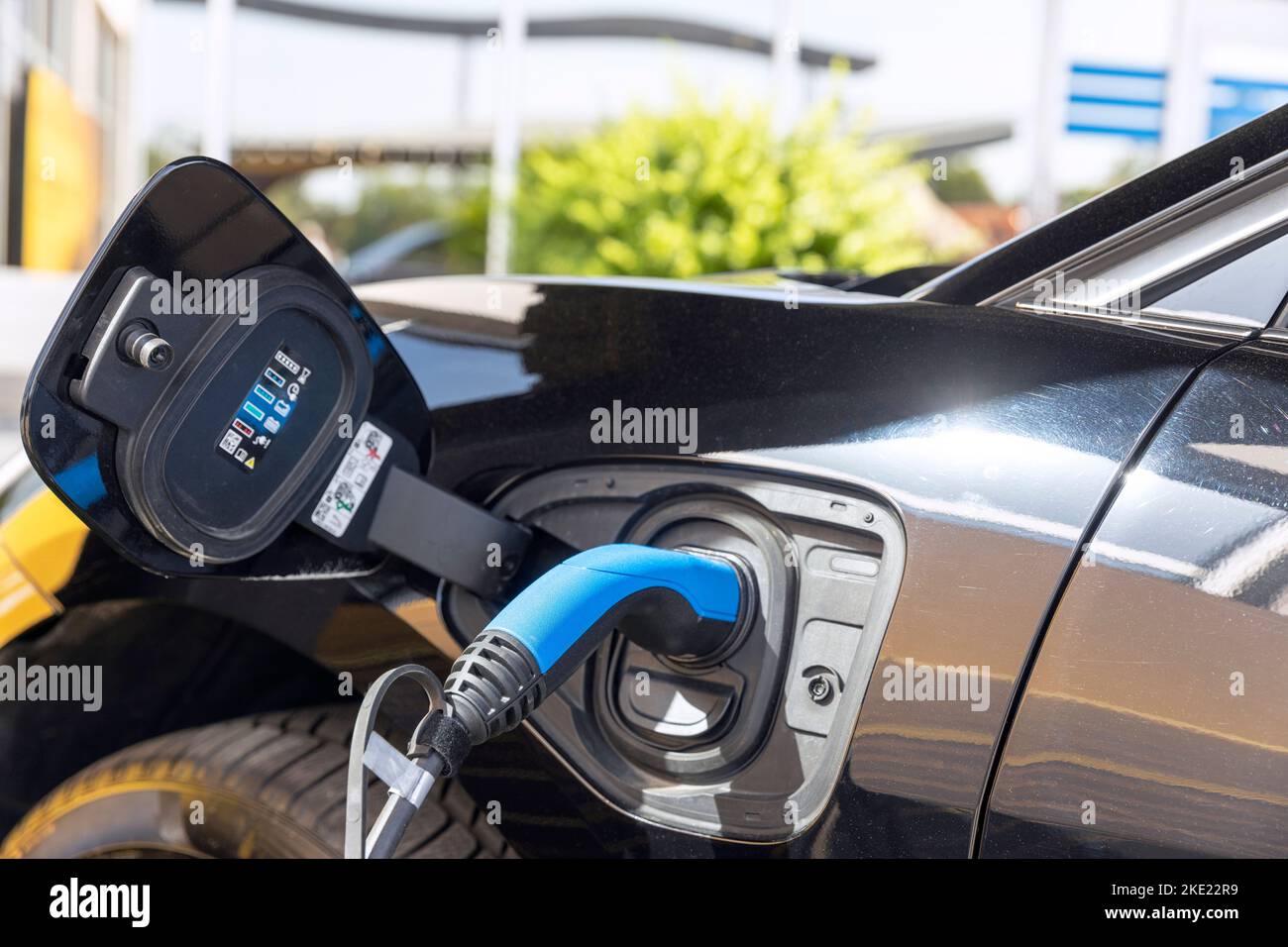 Electric vehicle with plug-in socket at charge station charging battery Stock Photo