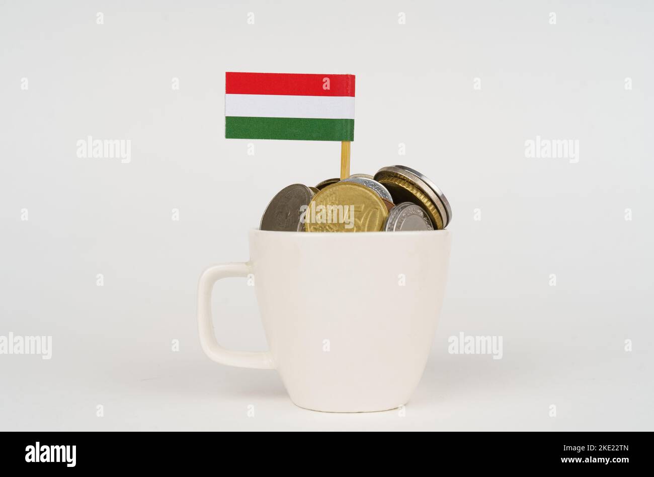 The flag of Hungary sticks out of a cup with coins. Economy and business concept. Stock Photo