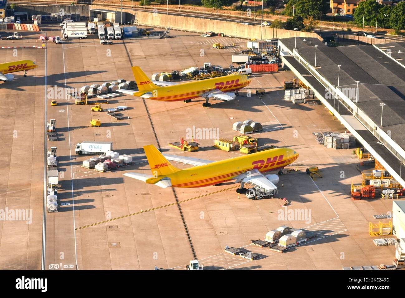 London, England - August 2022: Aerial view of cargo planes operated by DHL parked for unloading at the cargo terminal of an airport. Stock Photo