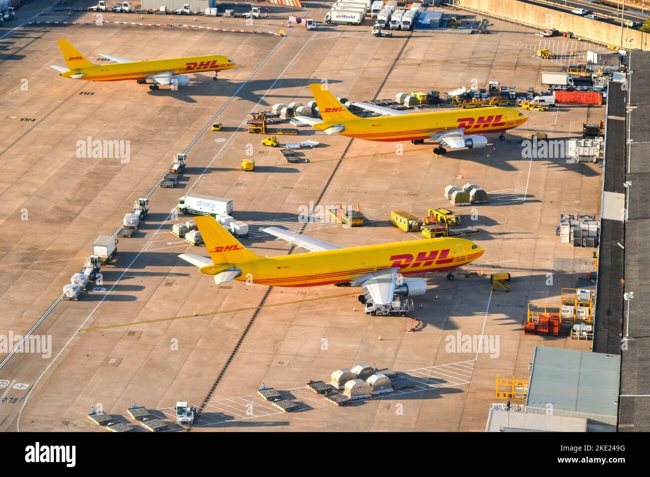 London, England - August 2022: Aerial view of cargo planes operated by DHL parked for unloading at the cargo terminal of an airport. Stock Photo
