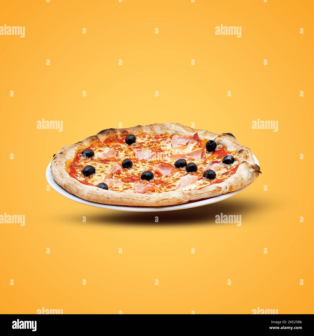 Homemade Italian pizza with cheese and olives  on a yellow background. Top view. Stock Photo