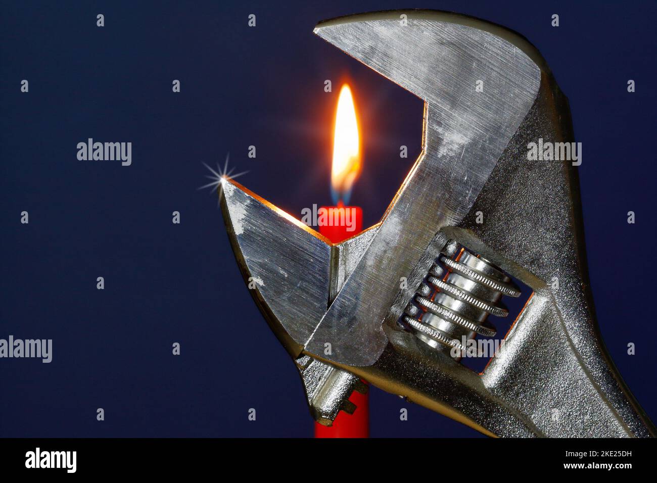 Christmas card theme for plumbers. Universal wrench with candlelight in the background. Stock Photo