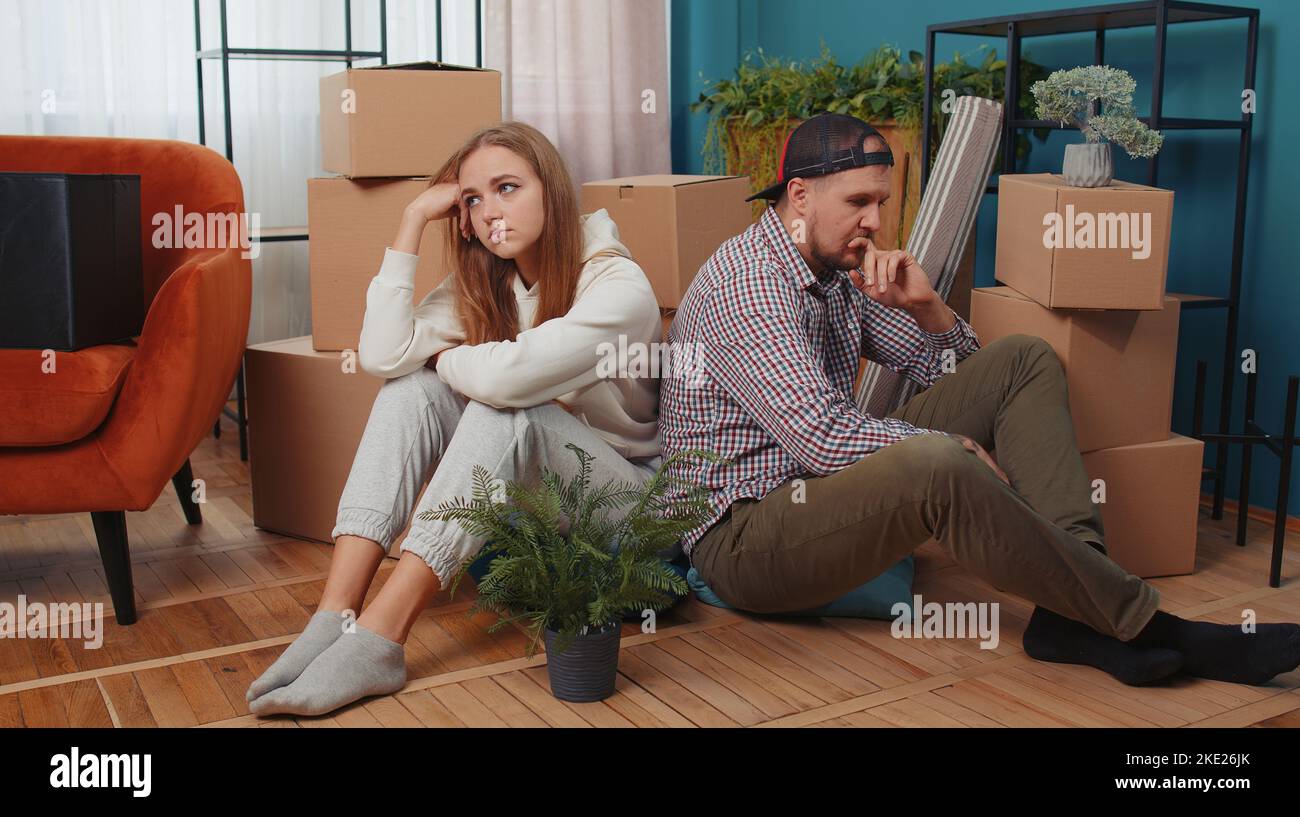 Sad tired married couple man woman leave house sit on floor near