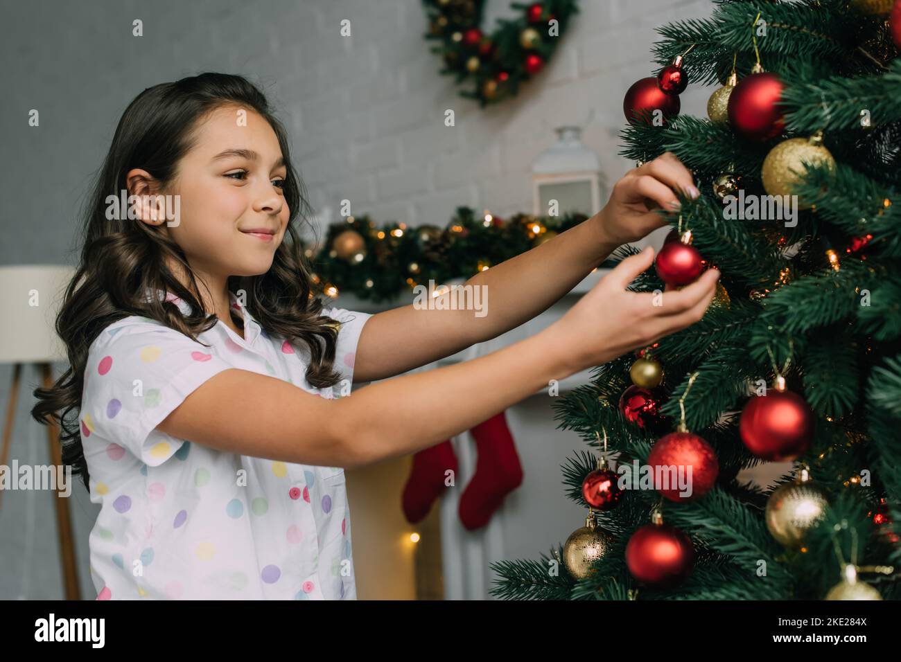 Smiling preteen girl decorating Christmas tree in living room Stock ...