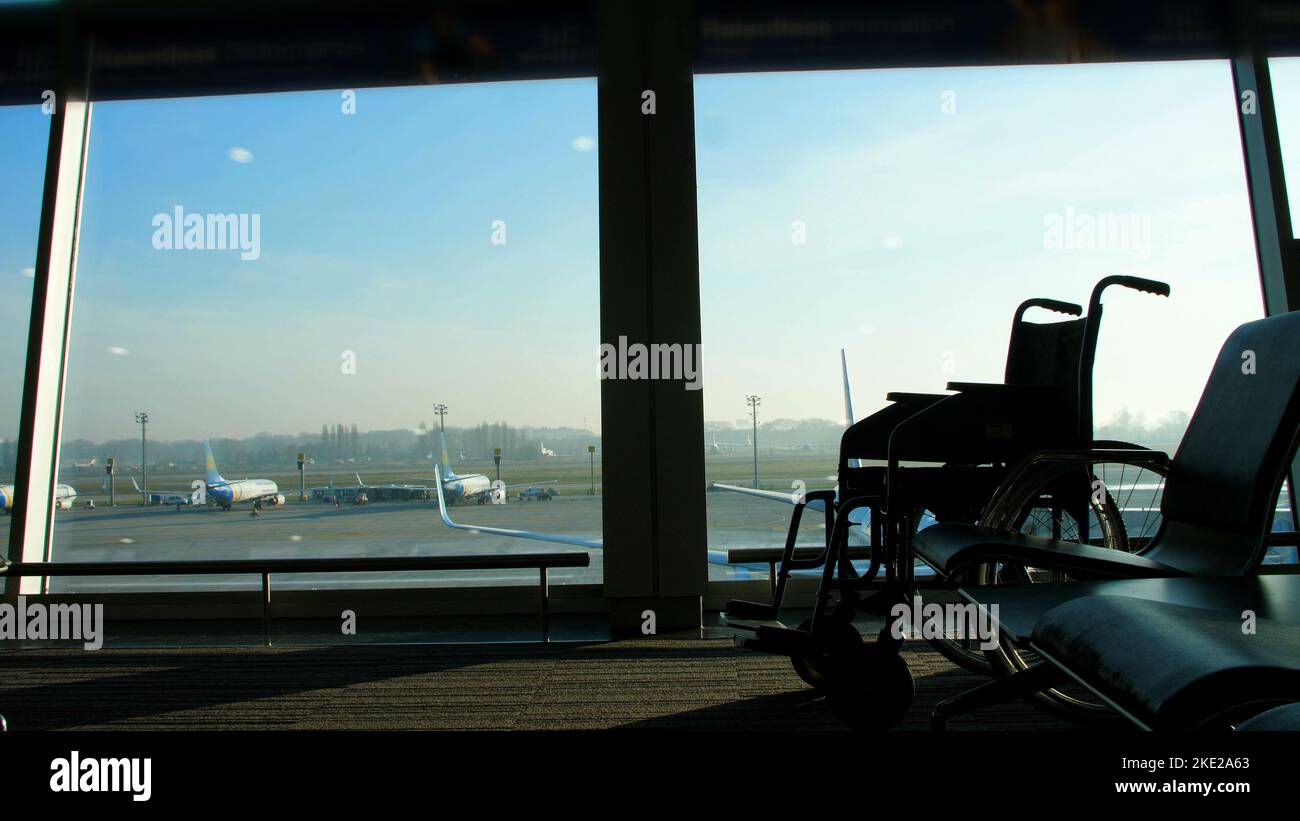 at the airport, in the waiting room, against the background of the window overlooking the aircraft and the runway, is a wheelchair, you can see its outlines. High quality photo Stock Photo