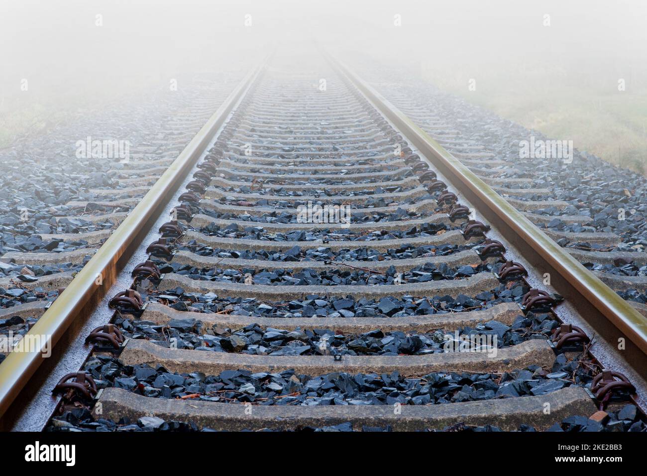 Abandoned railway tracks disappear in the thick wall of fog. Stock Photo
