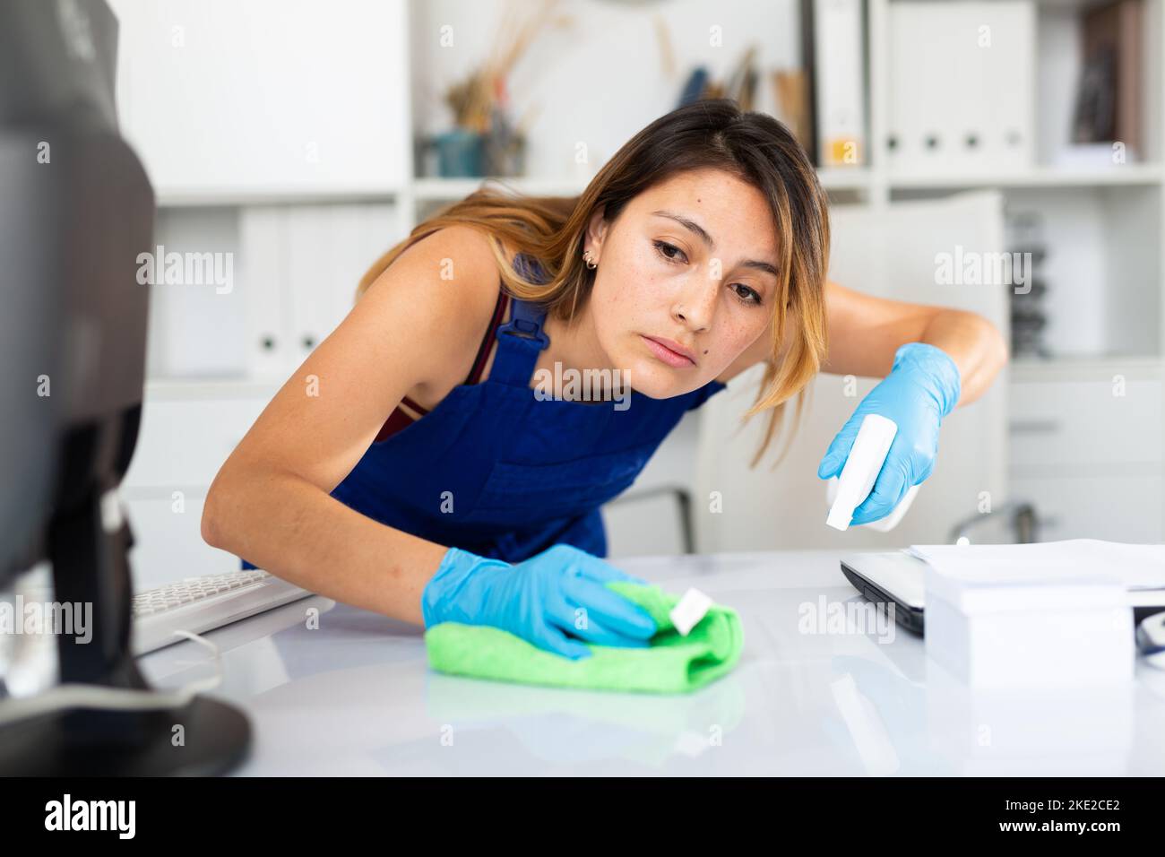 Mexican woman wearing uniform cleaning table in office Stock Photo Alamy
