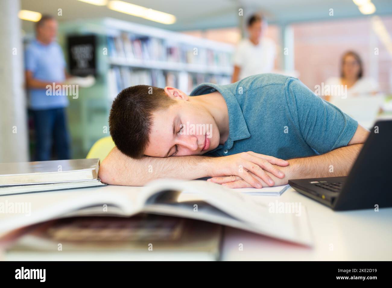 View on tired young male student sleeping in the school library Stock ...