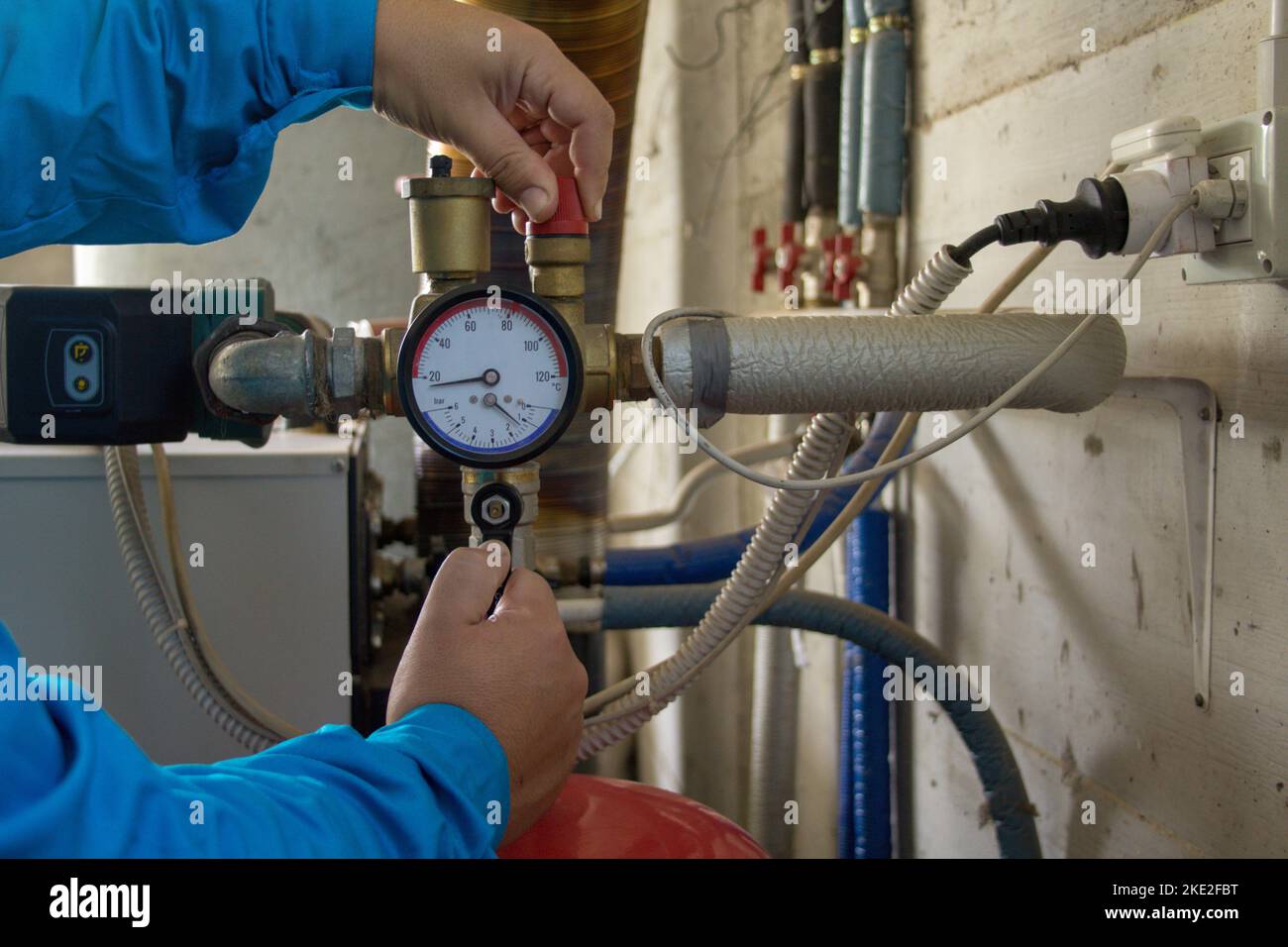 Image of the hands of a plumber who opens a hot water tap of a boiler