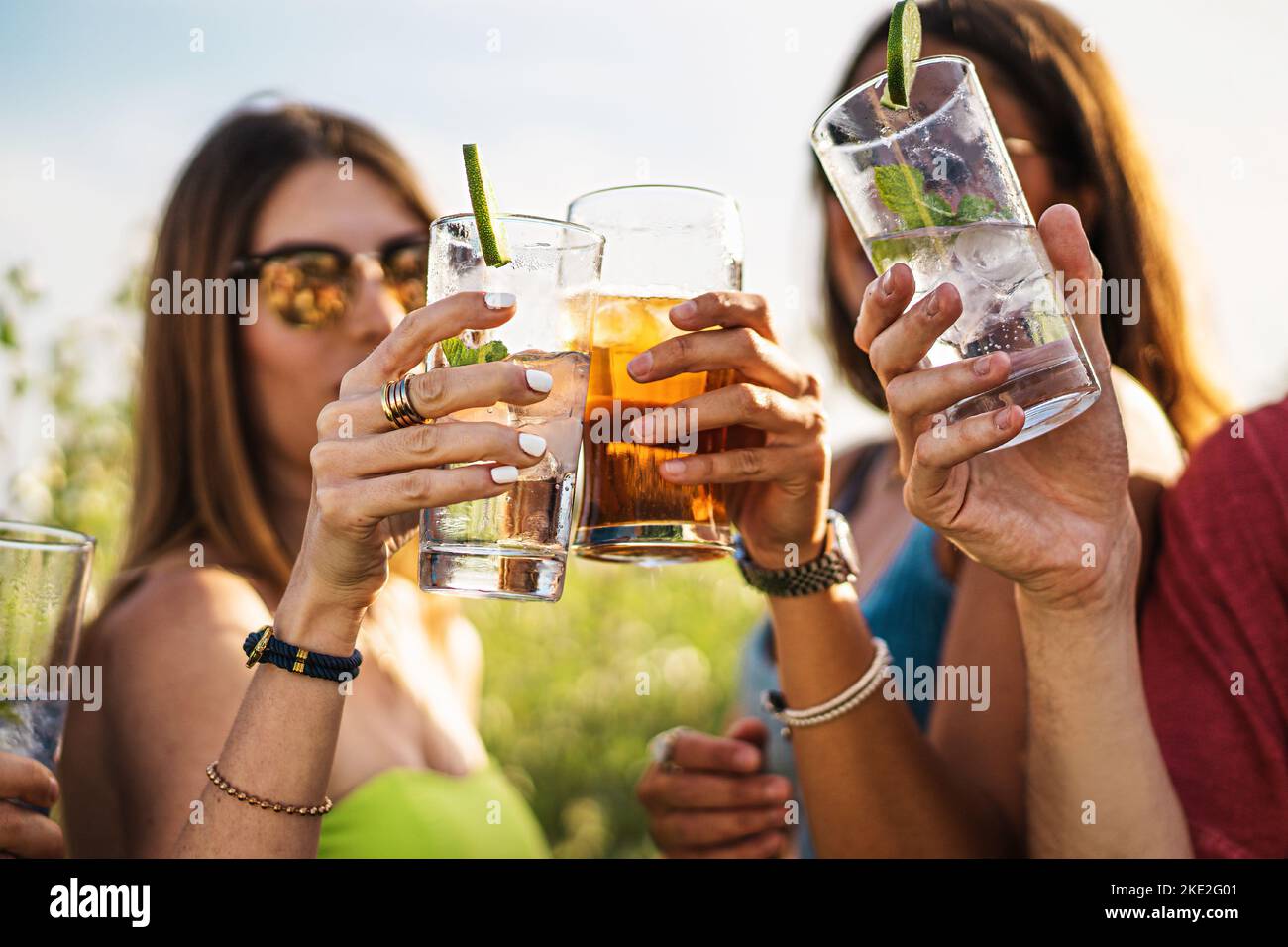 Cheerful group of millennial friends toasting alcoholic cocktails in