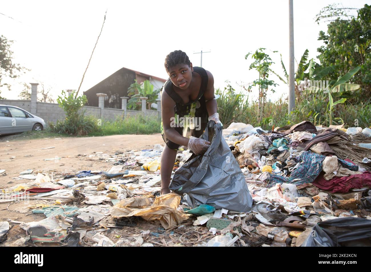 Young African girl picks up garbage thrown there in the open air ...