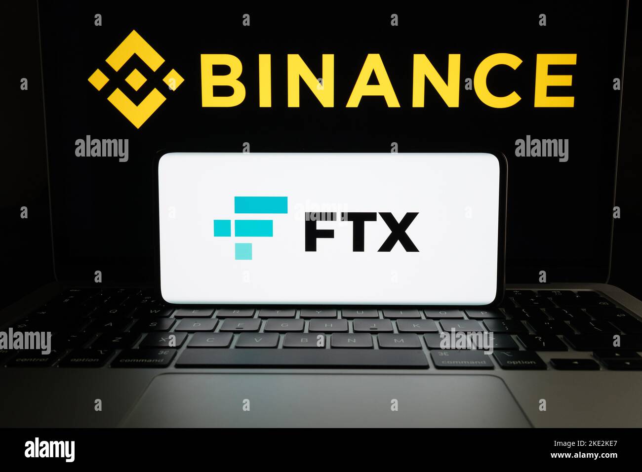 Binance and FTX Cryptocurrency Exchange merger concept. FTX logo seen on smartphone and blurred Binance logo on the laptop. Stafford, United Kindom, N Stock Photo