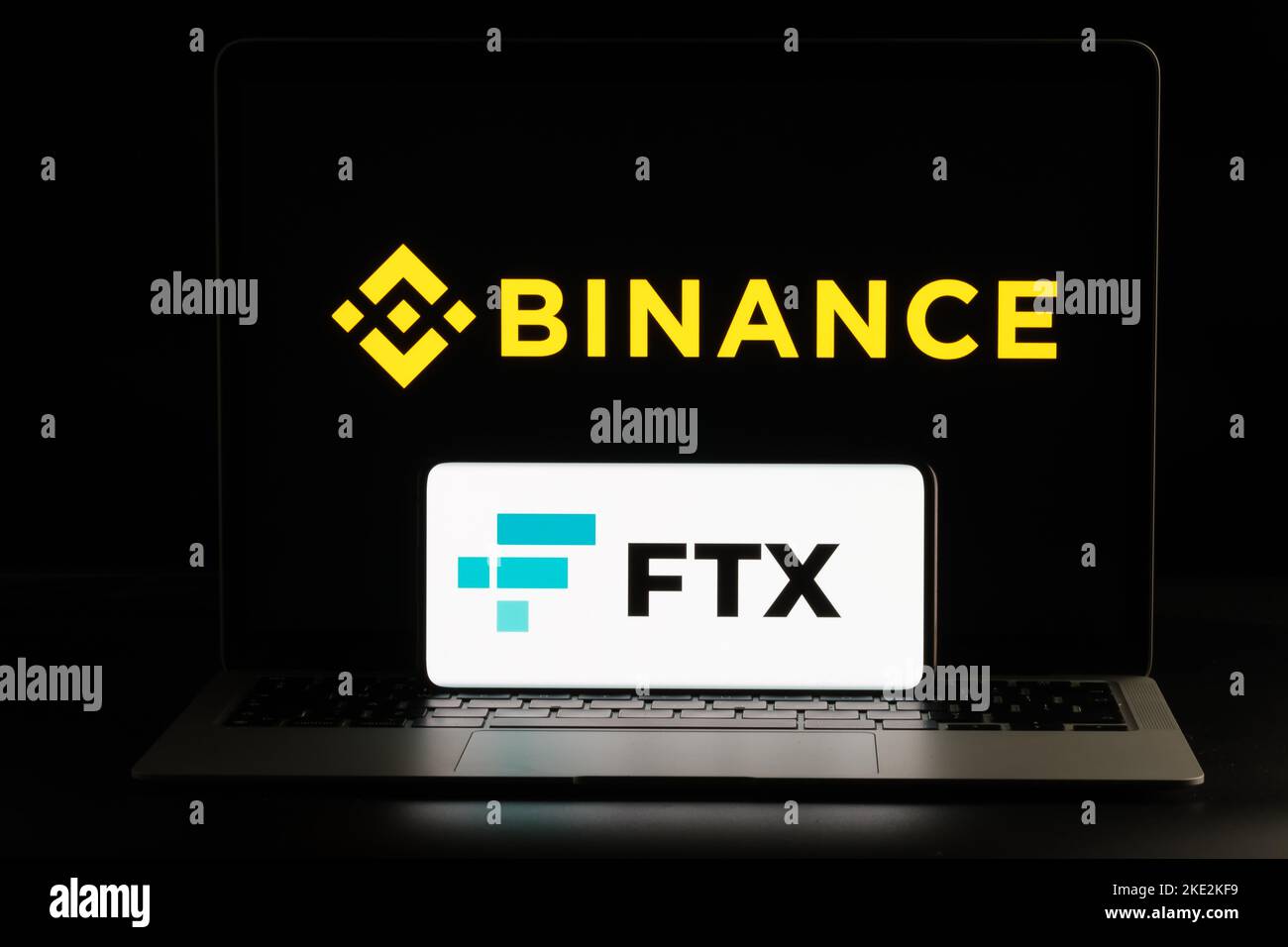 Binance and FTX Cryptocurrency Exchange merger concept. FTX logo seen on smartphone and blurred Binance logo on the laptop. Stafford, United Kindom, N Stock Photo