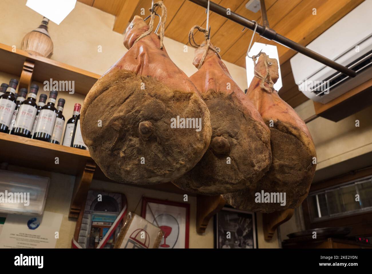 Prosciutto hang drying in the corner of a traditional trattoria in