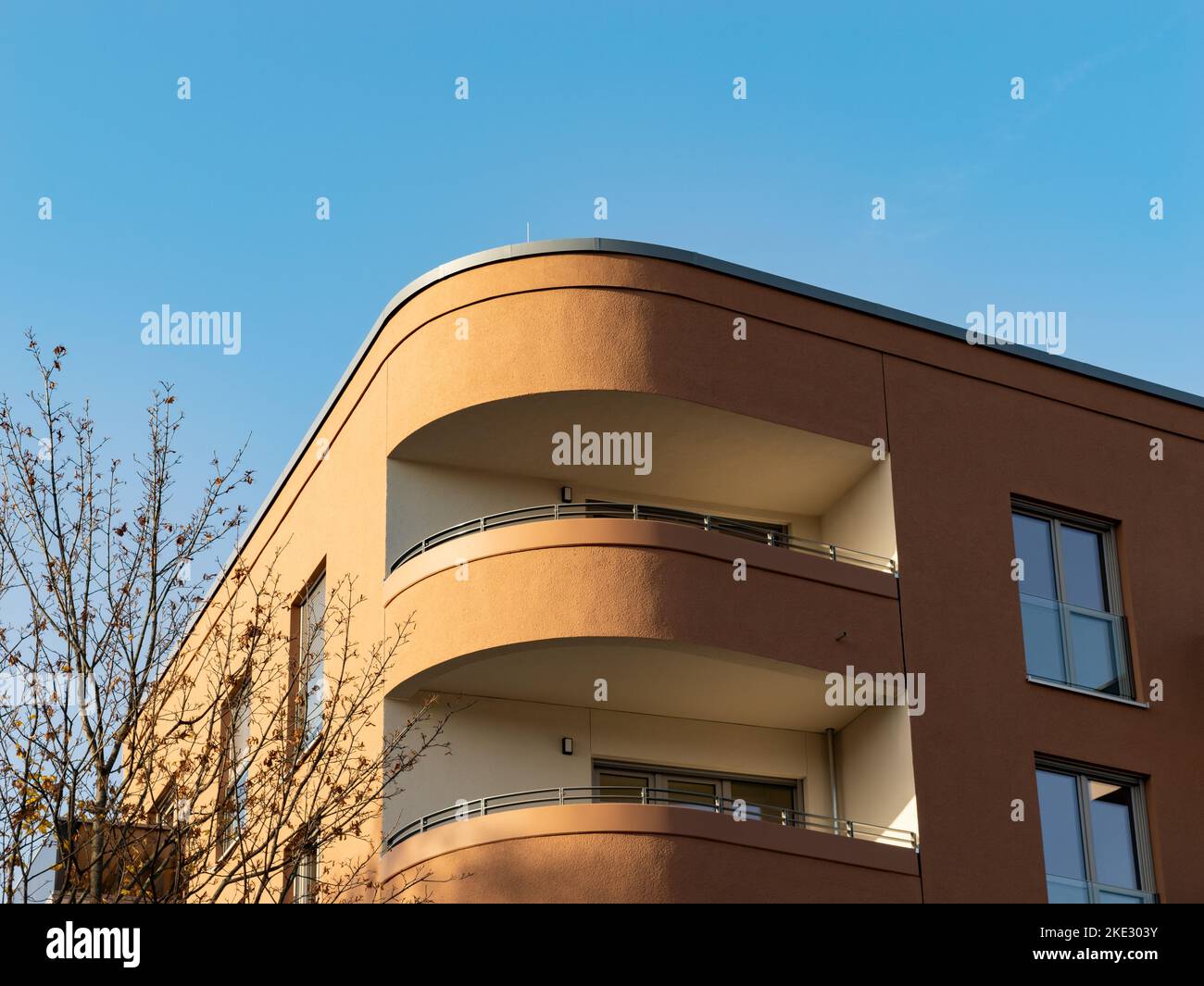 Modern balcony architecture. The facade is in a round shape at the corner of the building. The exterior is in brown color. Close-up of the design. Stock Photo