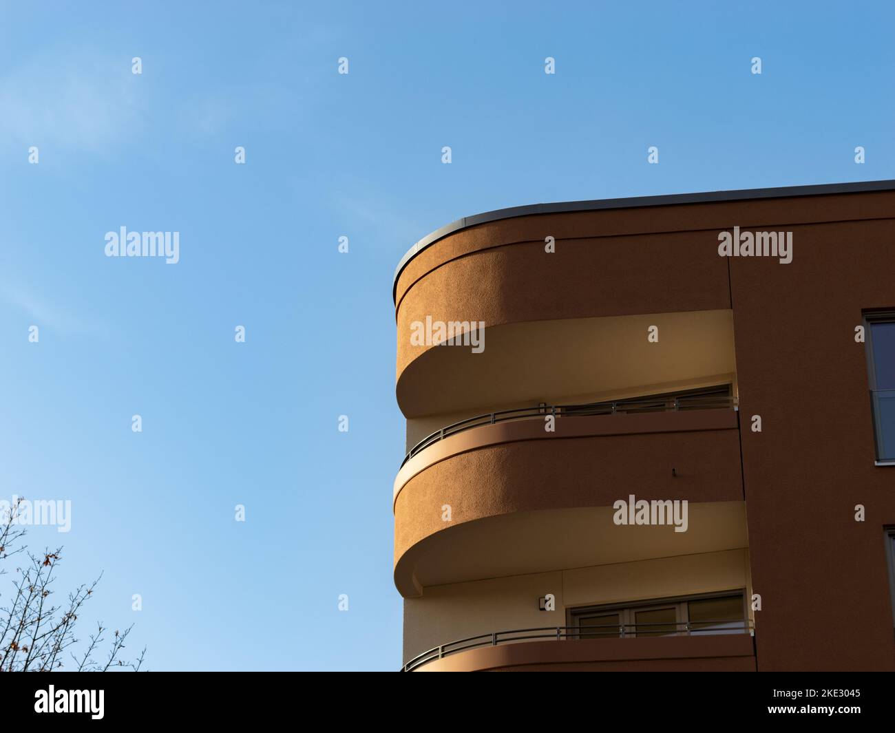 Modern balcony architecture. The facade is in a round shape at the corner of the building. The exterior is in brown color. Close-up of the design. Stock Photo